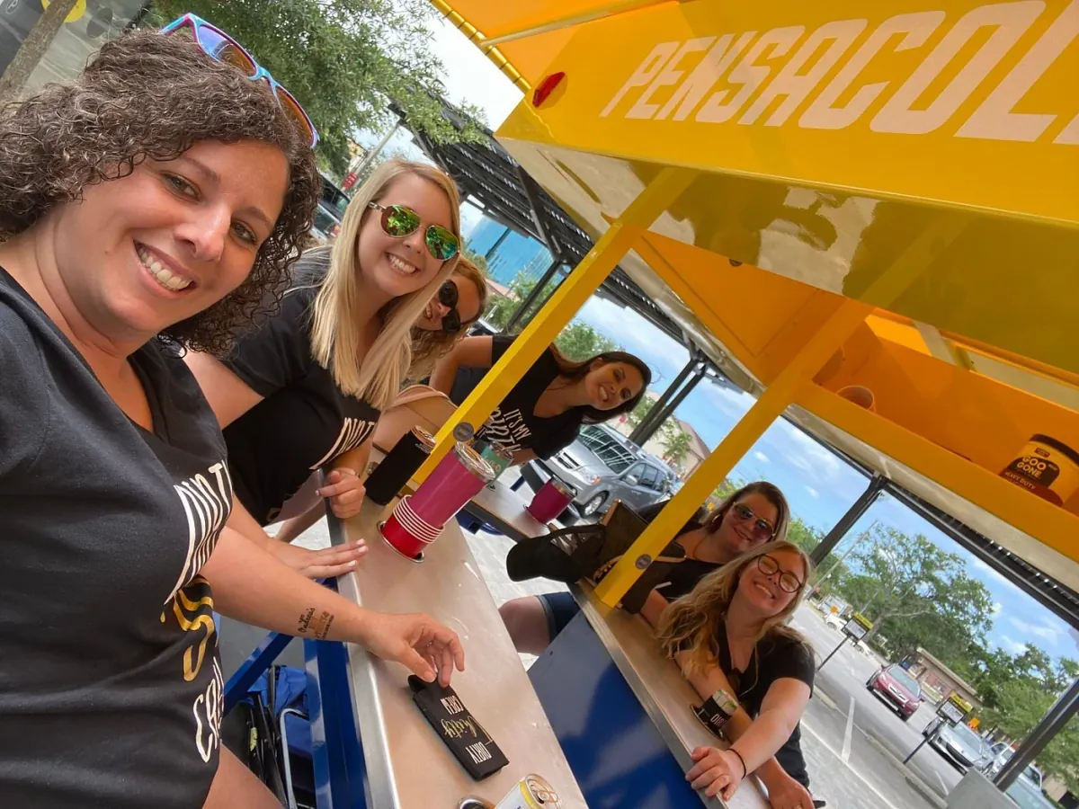 Friends taking a group selfie while riding the Pensacola Pedal Trolley